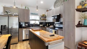 Une cuisine moderne dotée d’appareils électroménagers en acier inoxydable, de plans de travail en bois et d’un îlot central.