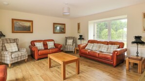 A living room with two leather sofas, a wooden coffee table, and plaid-patterned chairs.