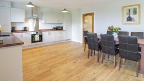 A modern kitchen with white cabinets, a wooden countertop, and a dining area with a table and chairs.