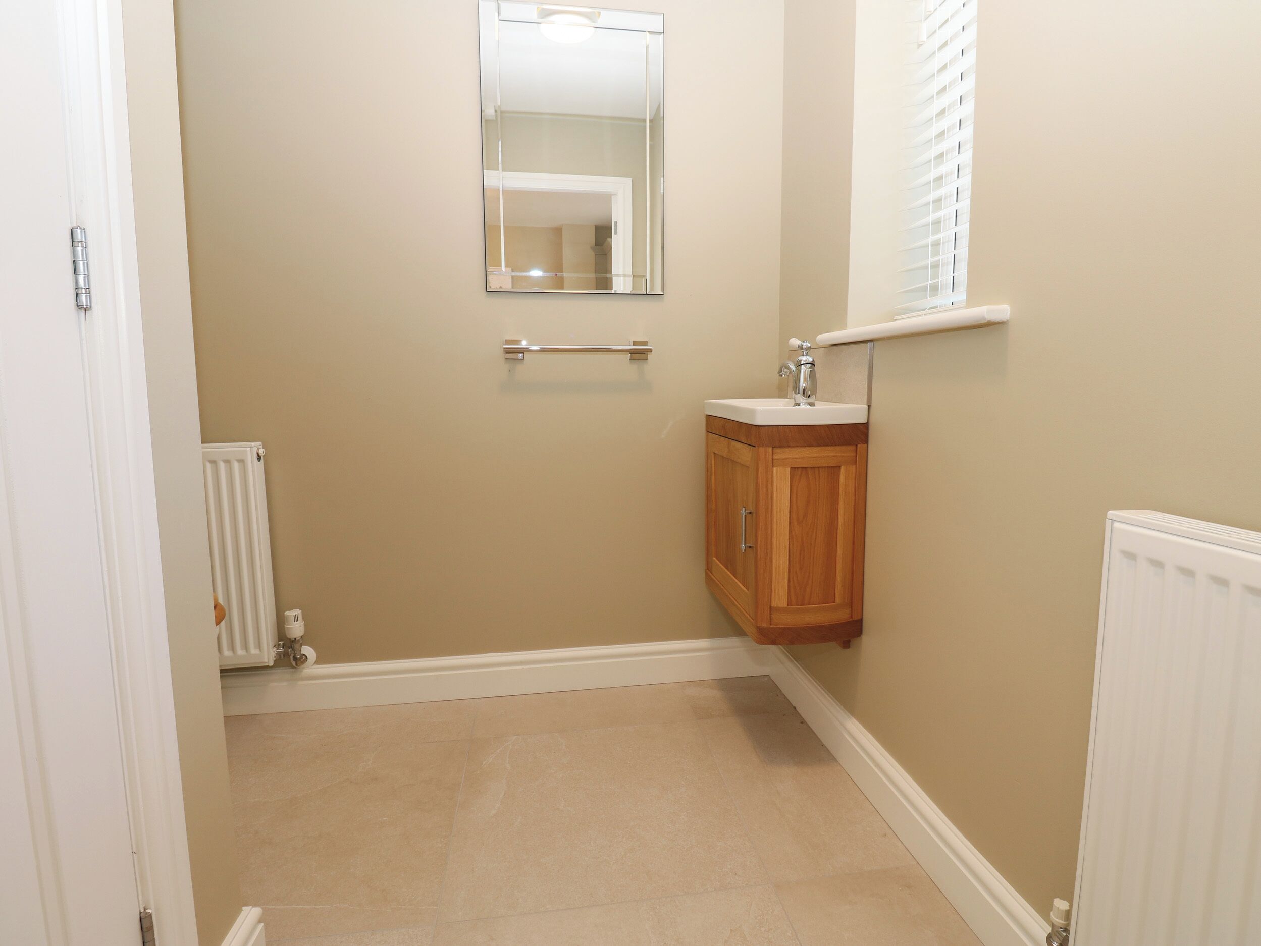 Une petite salle de bain avec un meuble en bois, un miroir et une fenêtre.