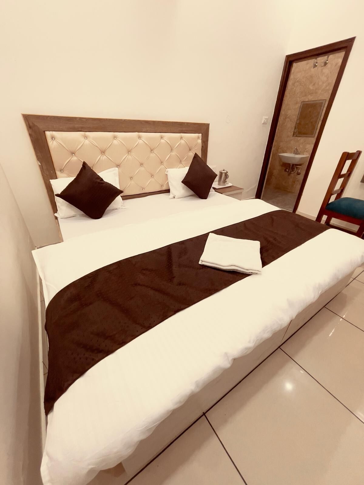 Una cama bien hecha con dosel acolchado, ropa de cama blanca y marrón, y una manta marrón.