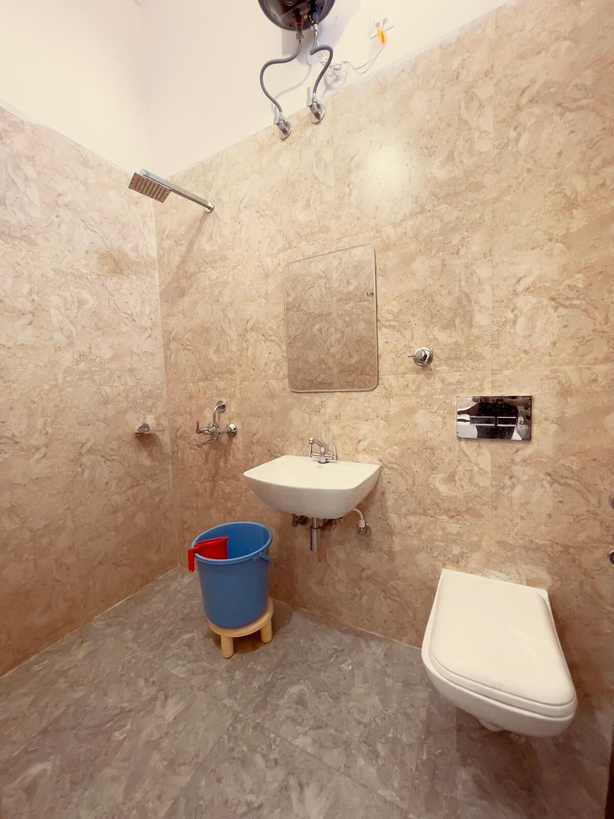 A bathroom with a white sink, a toilet, and a blue bucket on a stool.