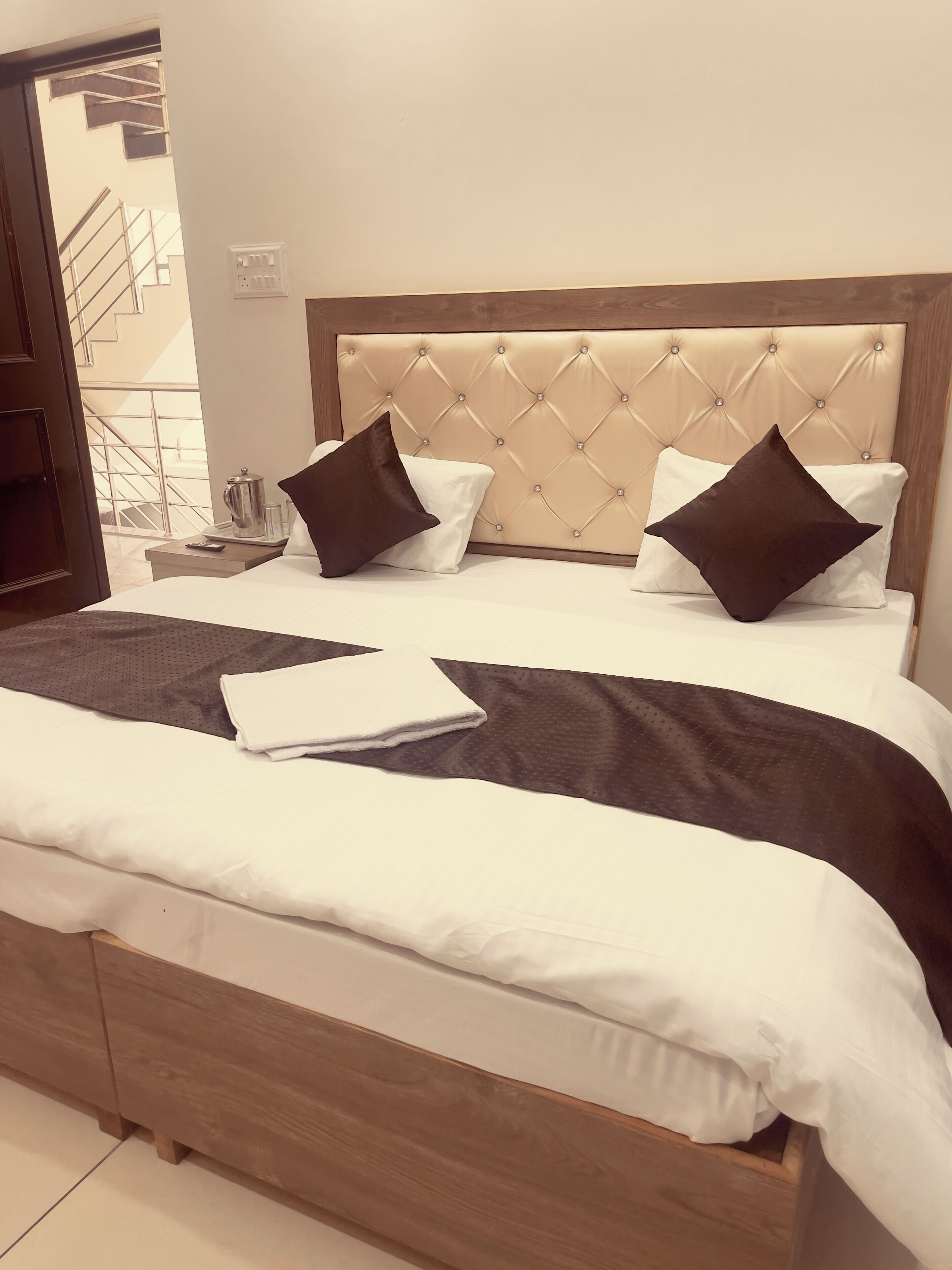 A neatly made bed with a wooden headboard, two pillows, and a folded white towel.