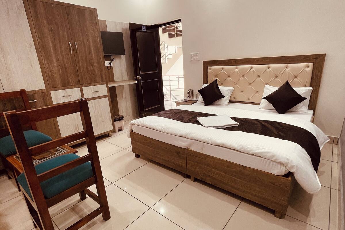 A bedroom with a bed, wooden wardrobe, and a chair.