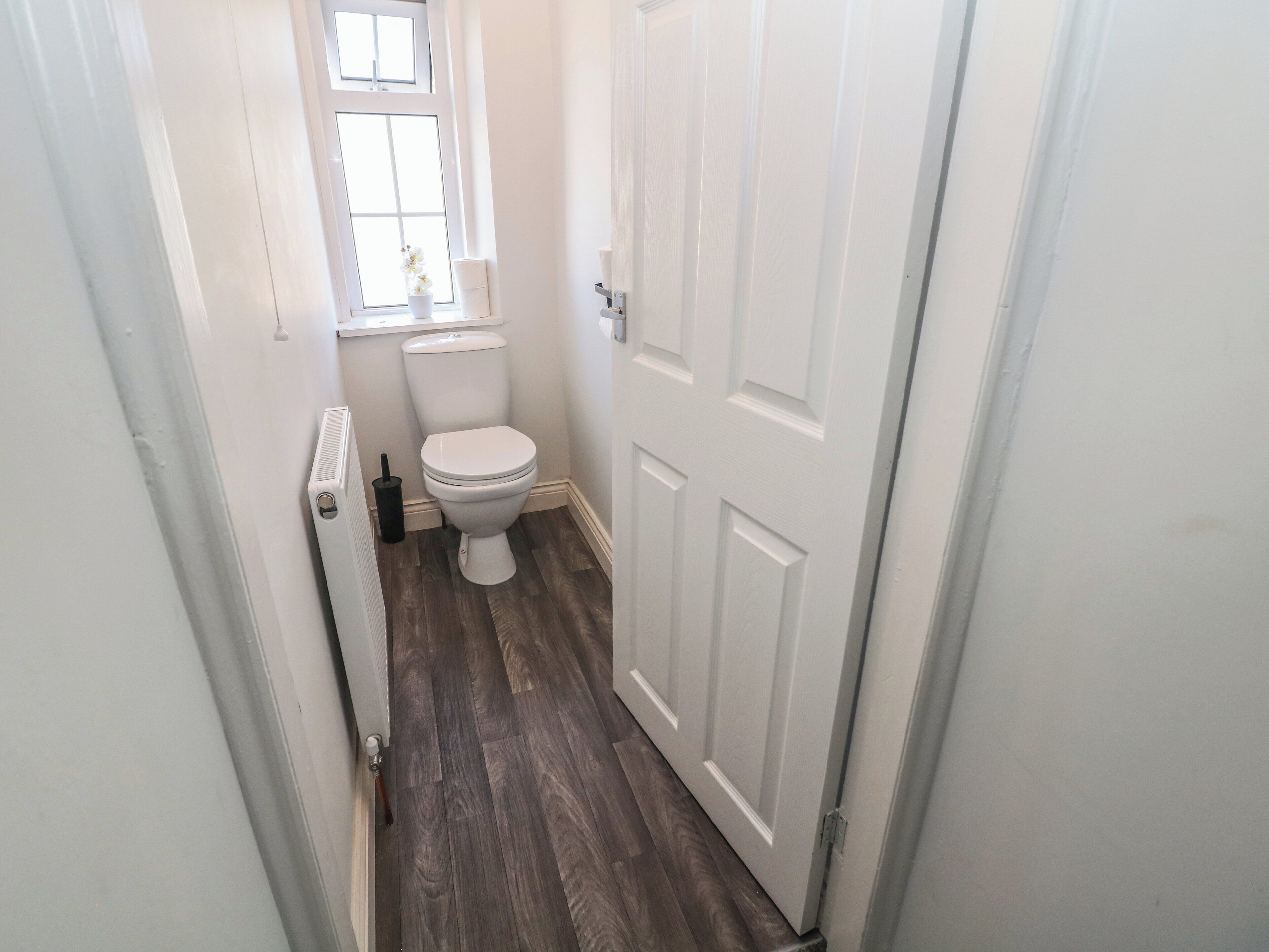 Un pasillo estrecho que conduce a un baño con inodoro, ventana y puerta.