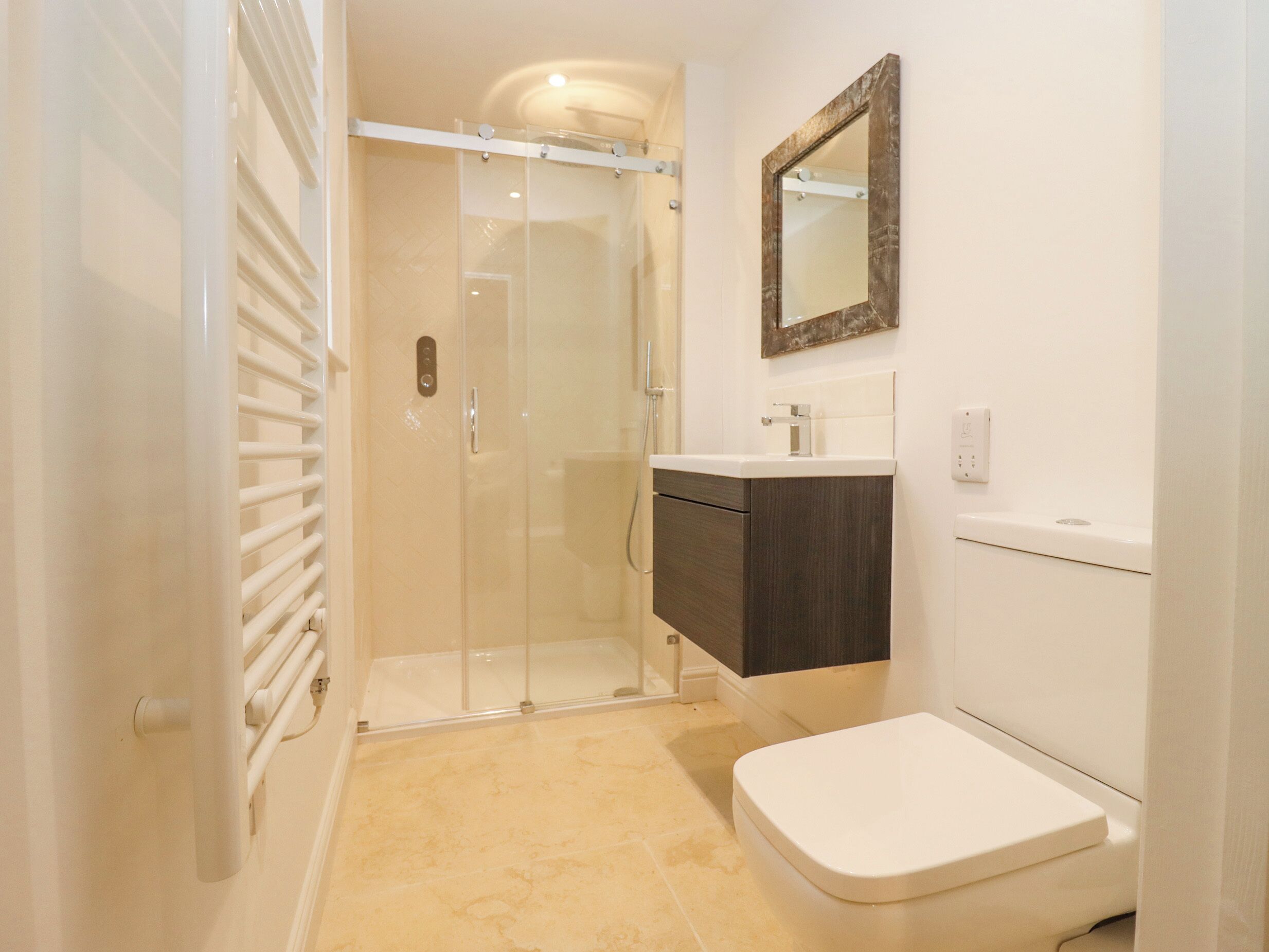A bathroom with a glass-enclosed shower, a dark wooden vanity, and a white toilet.