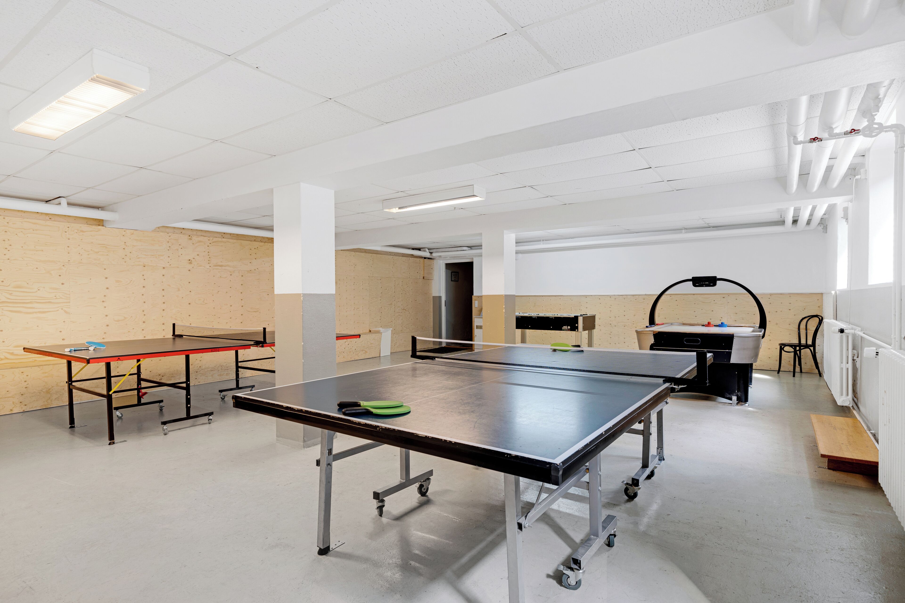 A spacious indoor area with ping pong tables, a pool table, and a billiards table.