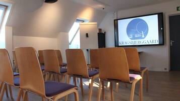 A conference room with wooden chairs and a large screen displaying 'KRAGSBJERGAARD'.