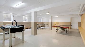A spacious indoor area with two foosball tables and a ping pong table.