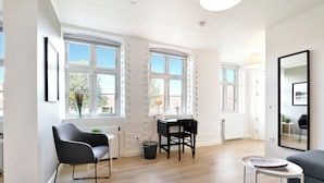 A modern, well-lit room with large windows, a desk, and seating areas. - Kragsbjerggaard Hotel (Odense)