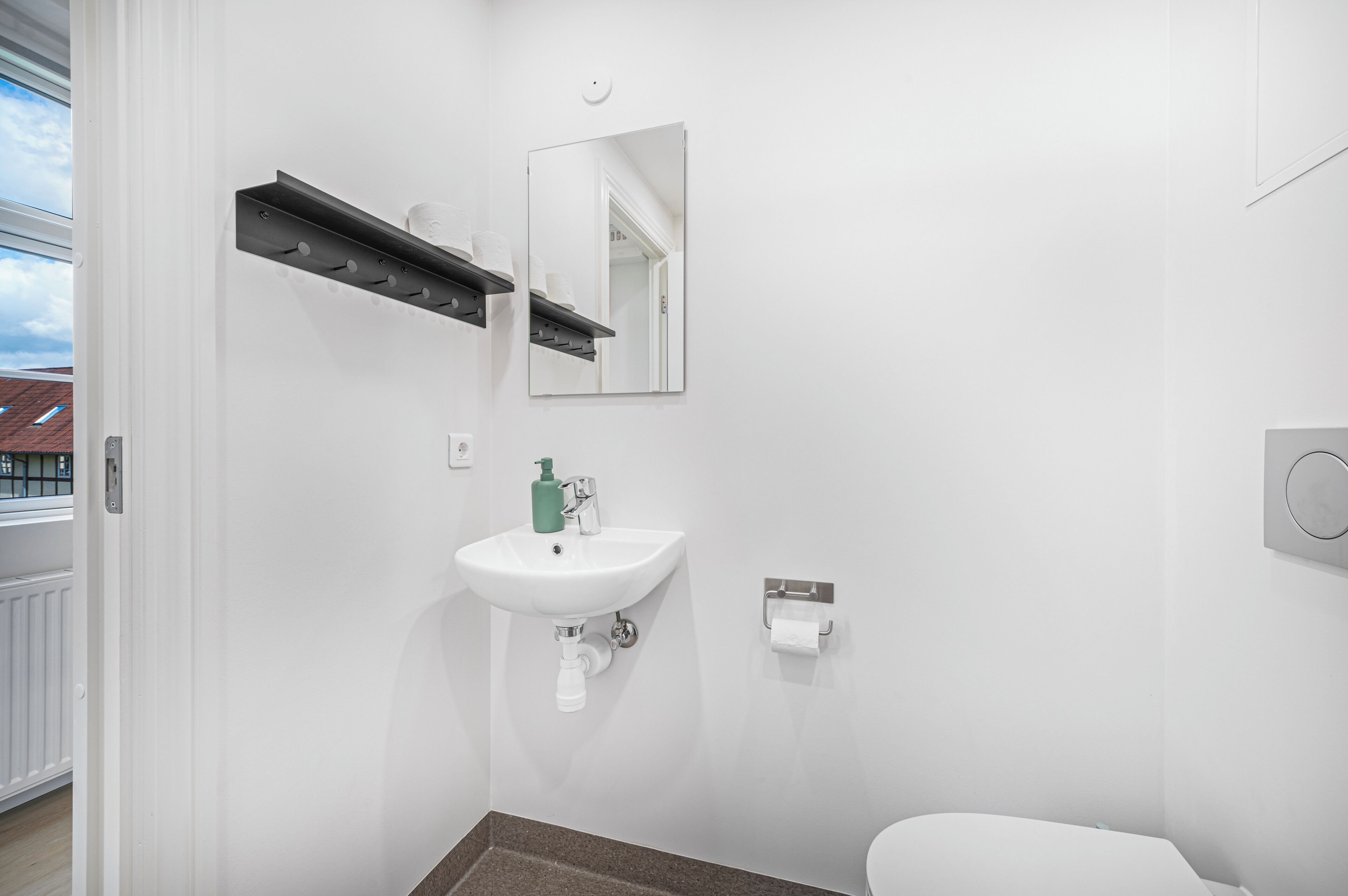 A modern bathroom with a white sink, mirror, and towel dispenser.