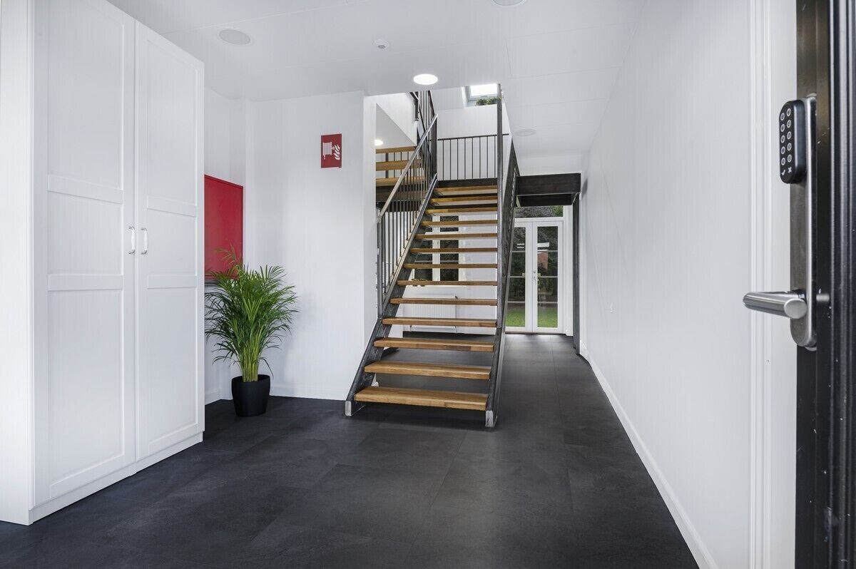 Un interior moderno con una escalera, paredes blancas y una planta en maceta.