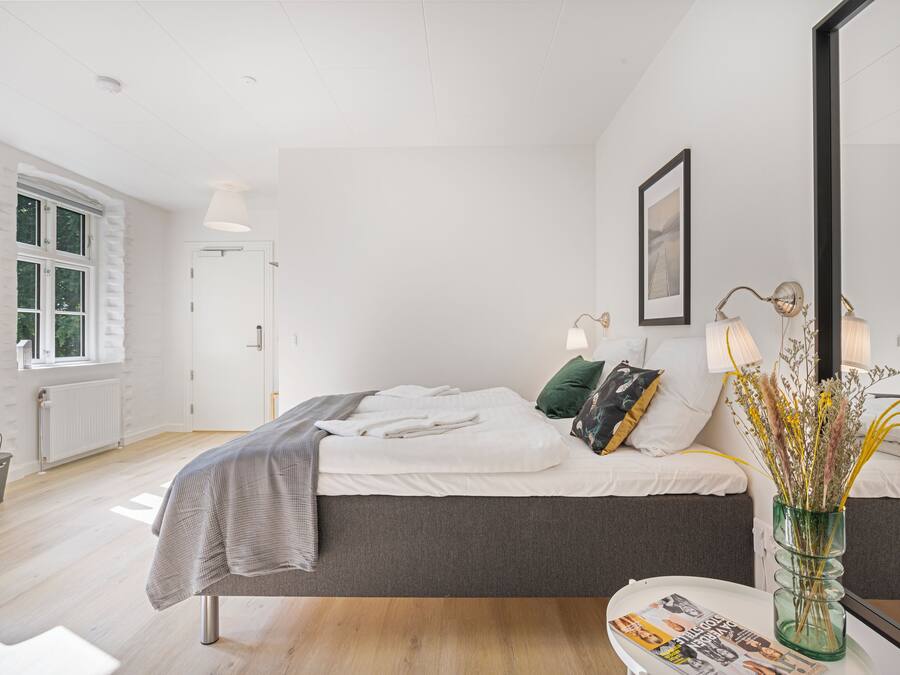 Un dormitorio moderno con una cama grande, lámparas de noche, un espejo y una ventana.