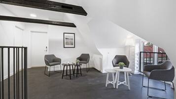 A modern loft with exposed beams, a staircase, and a seating area with chairs and tables.