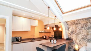 A modern kitchen with a central island, bar stools, and pendant lighting. - Fenty's (Windermere)