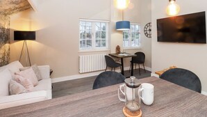 A modern living room with a sofa, coffee table, and a TV mounted on the wall. There are two hanging light bulbs and a floor lamp. - Fenty's (Windermere)