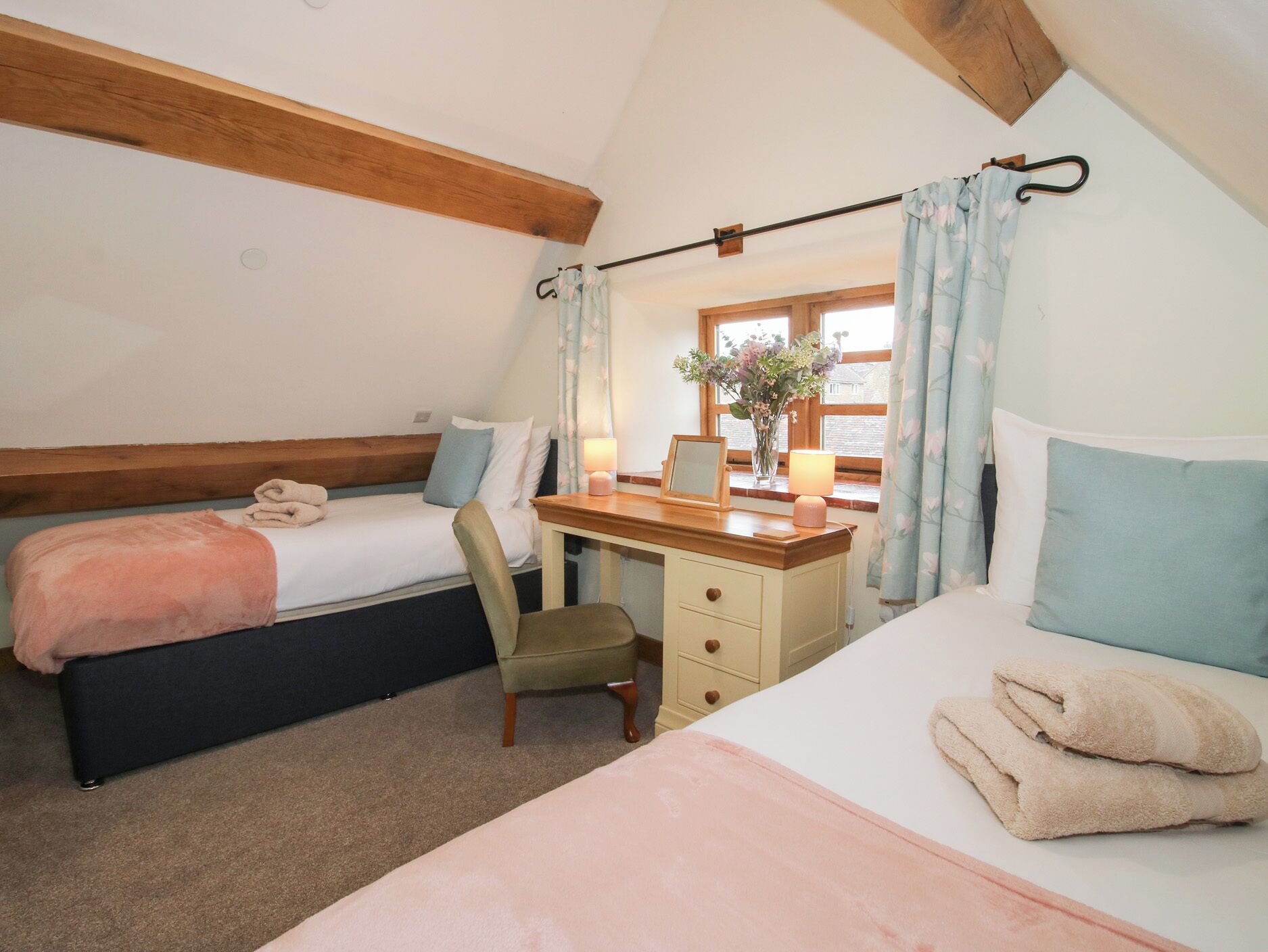 Une chambre confortable avec deux lits, un bureau et une fenêtre avec des rideaux.