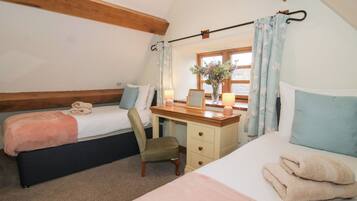 Une chambre confortable avec deux lits, un bureau et une fenêtre avec des rideaux.