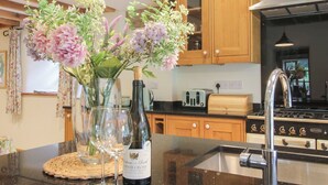 Une cuisine avec des meubles de rangement en bois, un évier en acier inoxydable et un plan de travail sur lequel se trouvent une bouteille de vin et des verres.
