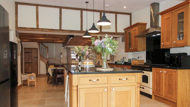 Une cuisine avec des meubles en bois, un îlot central et une cuisinière.