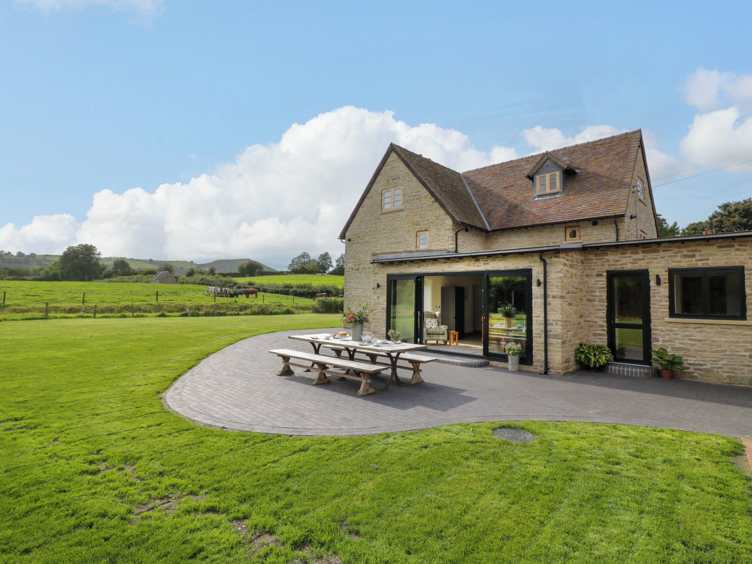 A stone farmhouse with a patio and a view of the countryside.
