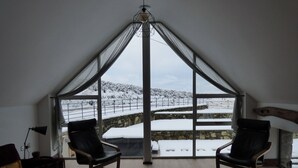 A room with two leather chairs, a chessboard, and a view of a snowy landscape through large windows. - Merddwr (Corwen)