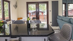 A dining area with a black countertop, chairs, and a table set for a meal. - Alfresco Lodge (Windermere)