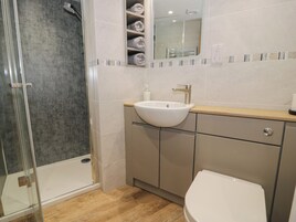 Un baño con cabina de ducha de vidrio, un lavabo blanco y un inodoro.