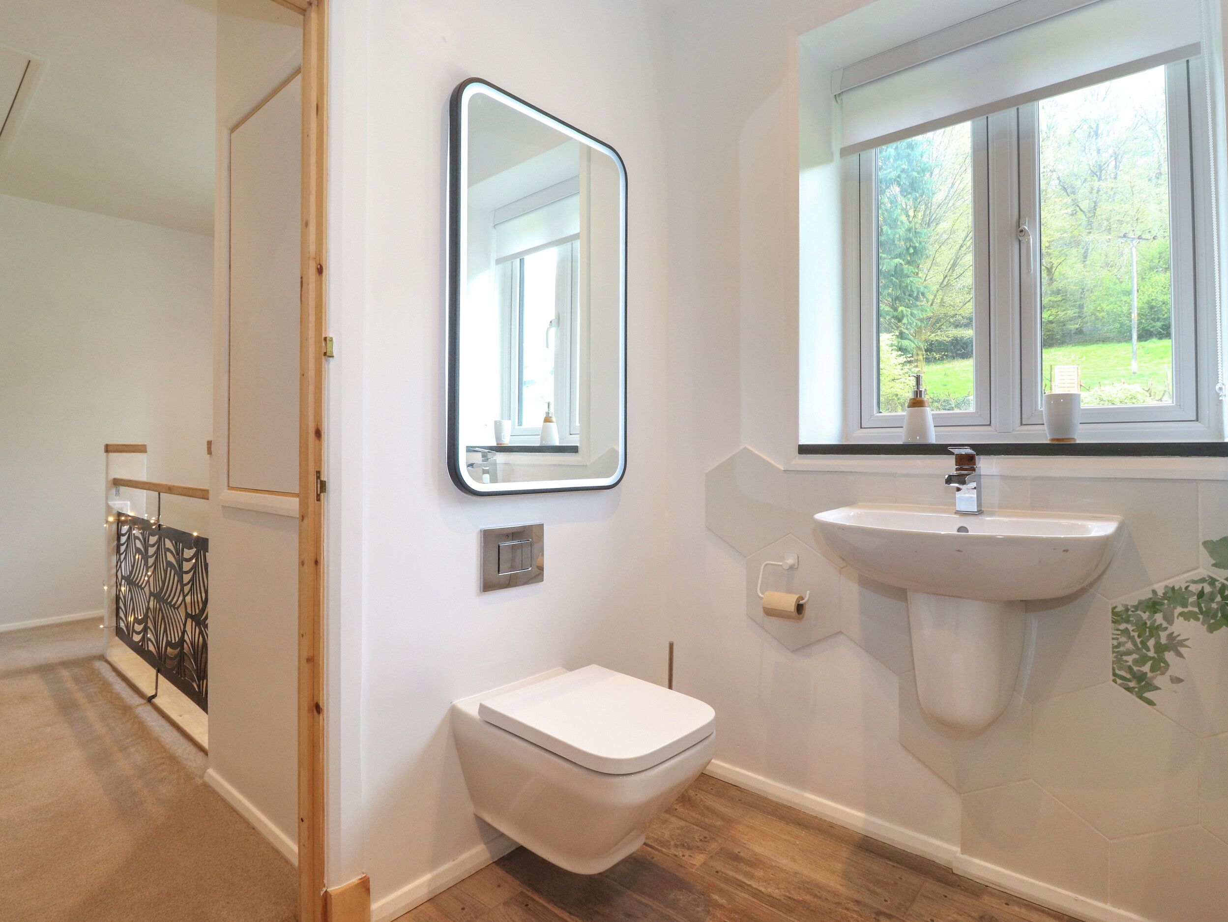 Een badkamer met toilet, wastafel, spiegel en raam.