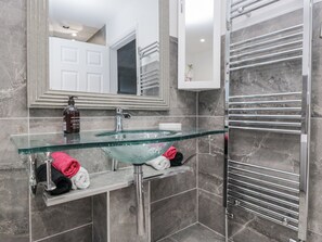 A modern bathroom with a glass sink, chrome fixtures, and a towel rack. - Hazelodge (Coniston)