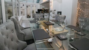 Un espace repas moderne avec une table en verre, des chaises à revêtement gris et une table à manger avec un plateau en verre.