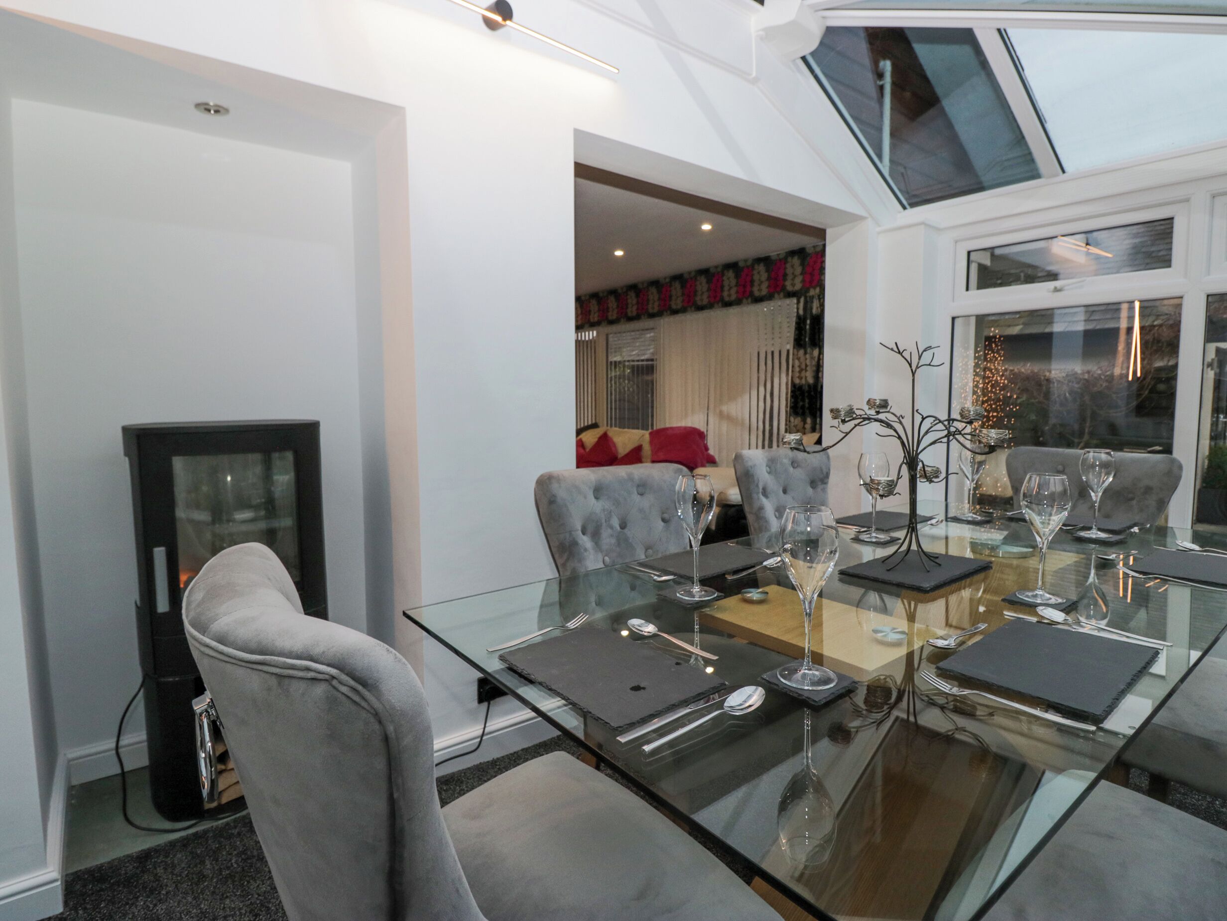A dining area with a glass table set for four, grey upholstered chairs, and a modern interior design.