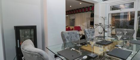 A dining area with a glass table set for four, grey upholstered chairs, and a modern interior design.