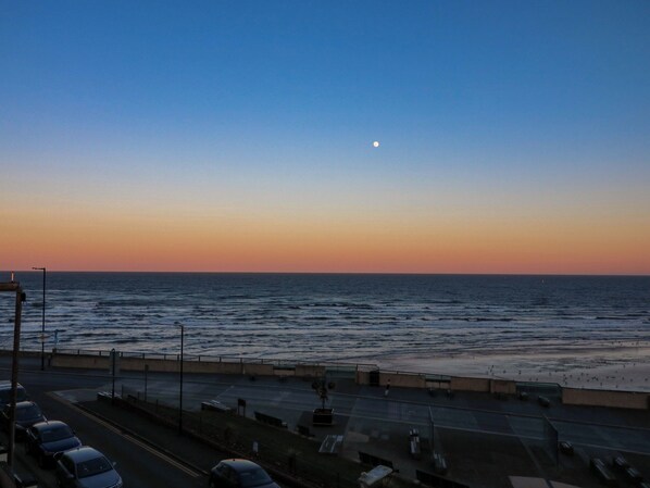 Une route côtière offrant une vue sur la mer et sur la lune dans le ciel.