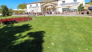 A building with a clock tower, outdoor seating, and a well-maintained lawn. - Apt 4 @ Hunter's Quay (Bridlington)