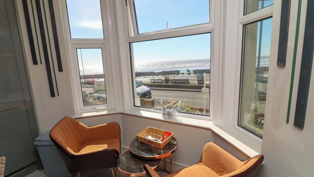 A corner room with two leather chairs, a small table, and a view of the sea through large windows. - Apt 4 @ Hunter's Quay (Bridlington)