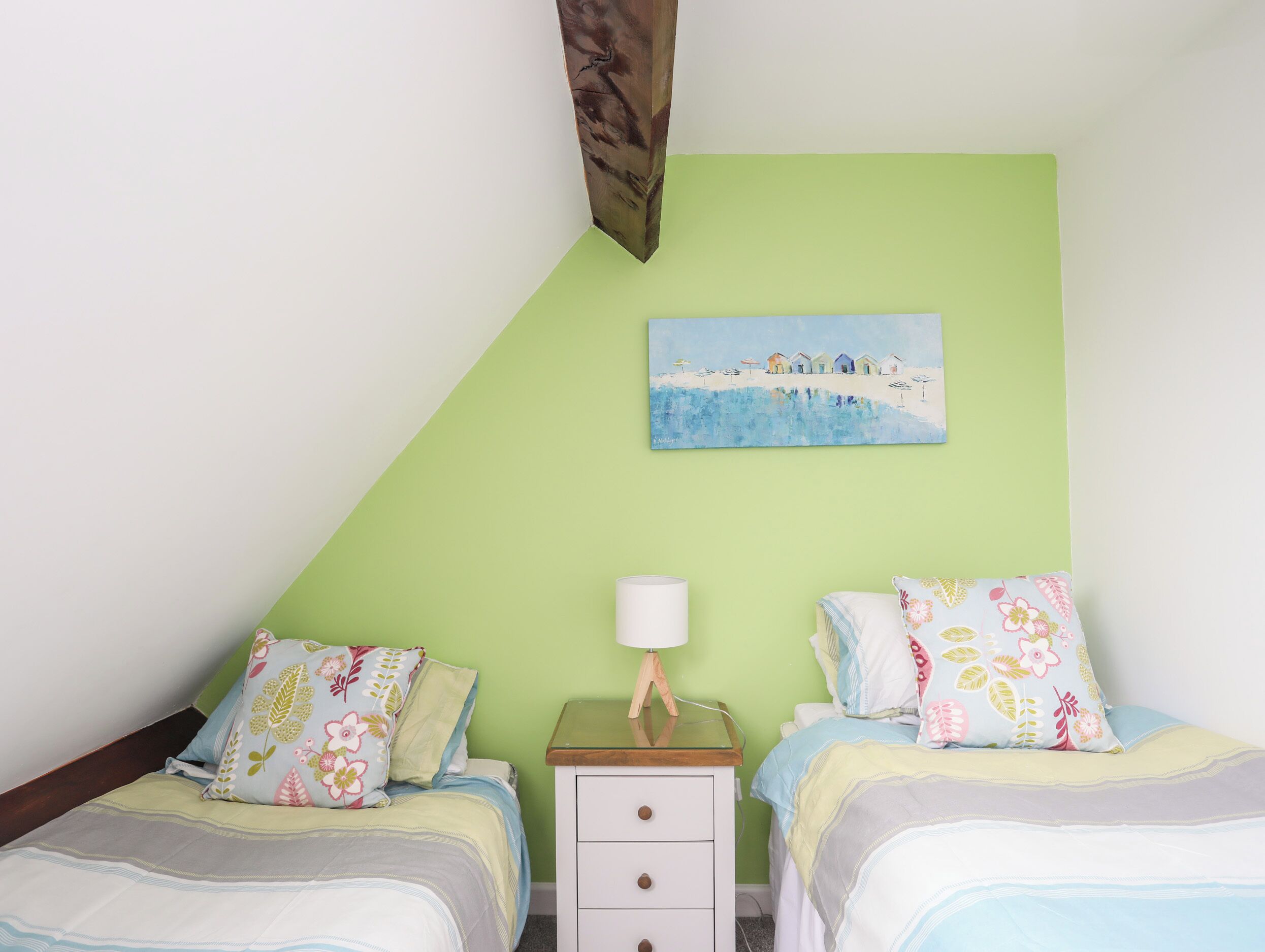 Una camera da letto con due letti, un comodino, una lampada e un quadro appeso al muro.