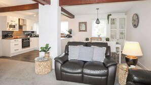 Una sala de estar moderna con un sofá de cuero, una mesa de centro de vidrio y un área de comedor al fondo.