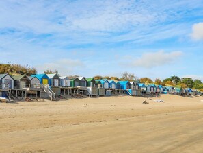 Een rij strandhutten met houten terrassen en trappen die erheen leiden, gelegen op een zandstrand.