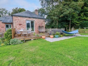 A brick house with a deck, outdoor seating, a hammock, and a fenced garden area. - The Old Watermill (Bodmin)