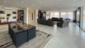 Ett rymligt vardagsrum med en stor soffgrupp, ett soffbord och en platt-TV som är monterad på väggen.