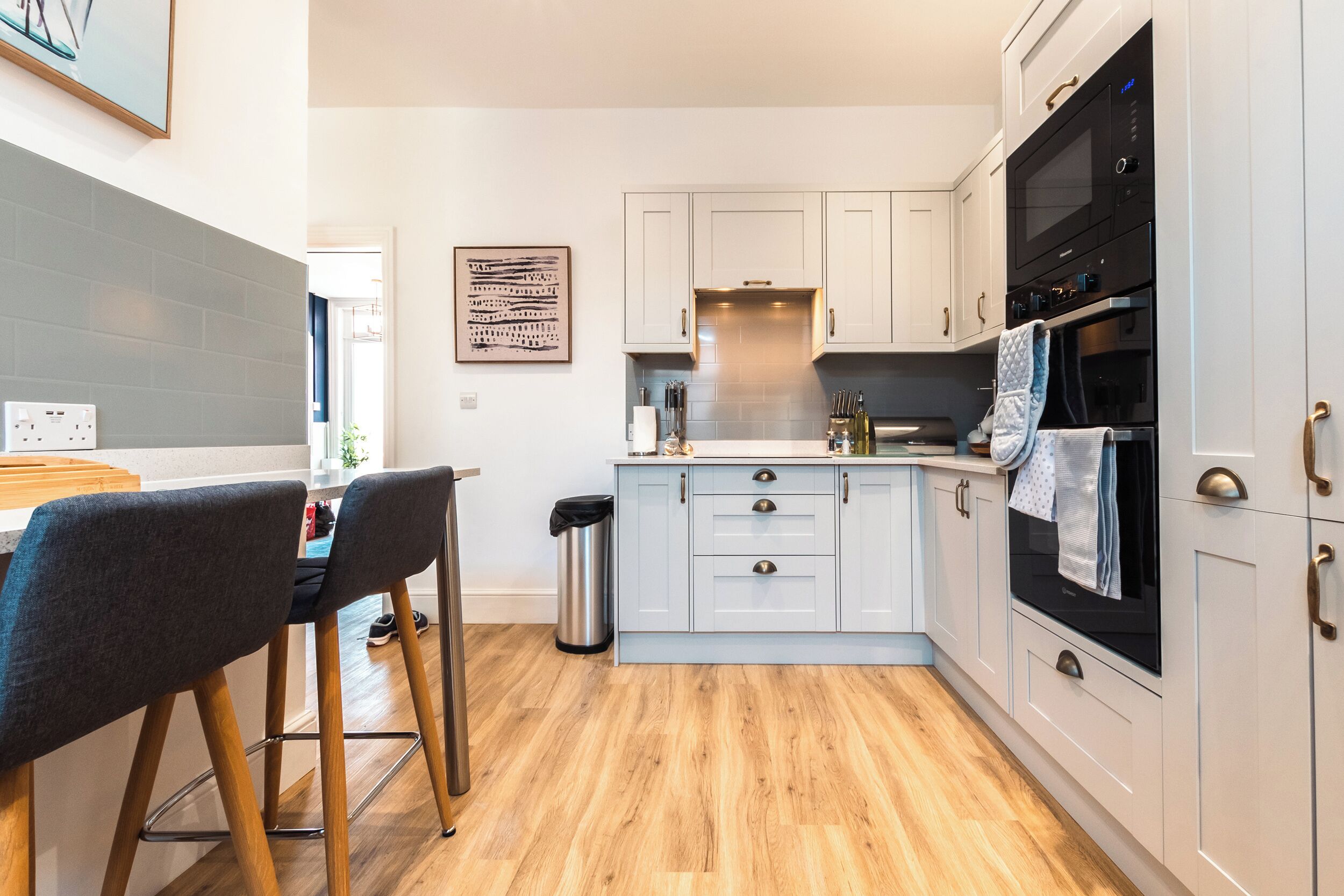 A modern kitchen with white cabinets, a black oven, and a stainless steel trash can.