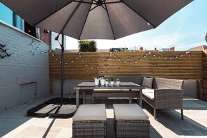 An outdoor patio with a table, chairs, and an umbrella. - Anchor House (Weymouth)