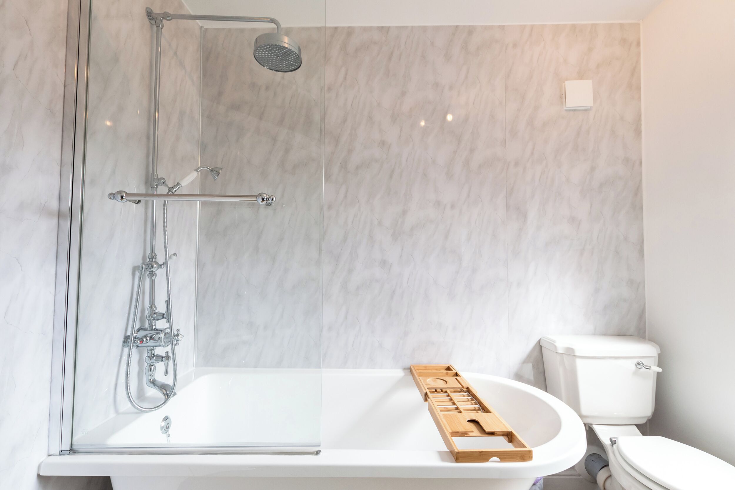 Un baño con ducha, inodoro y una bandeja de madera sobre el lavabo.