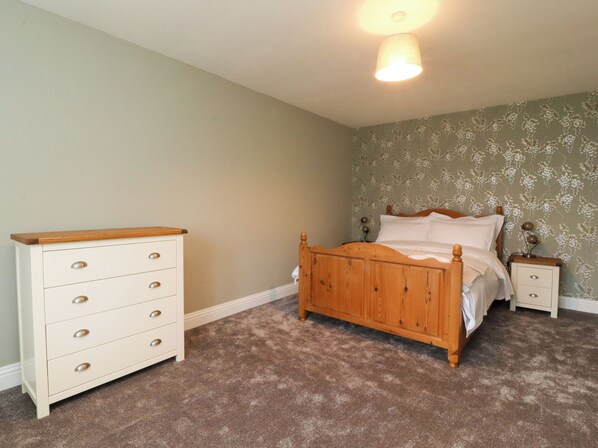 A bedroom with a wooden bed, a white dresser, and a nightstand.