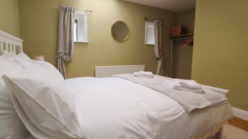 Un dormitorio con cama, ventana, radiador y espejo.