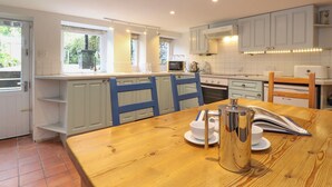 Una cocina moderna con armarios blancos, una mesa de comedor de madera y vistas al exterior.