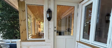 A wooden cabin with a front door, a small porch, and a window.