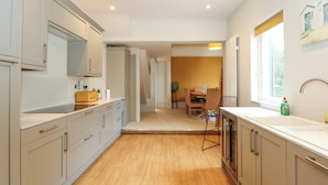 Uma cozinha moderna com piso de madeira clara, armários cinza e um espaço de jantar com mesa e cadeiras.
