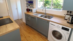 Cocina compacta con lavabo, microondas, tostadora y lavadora.